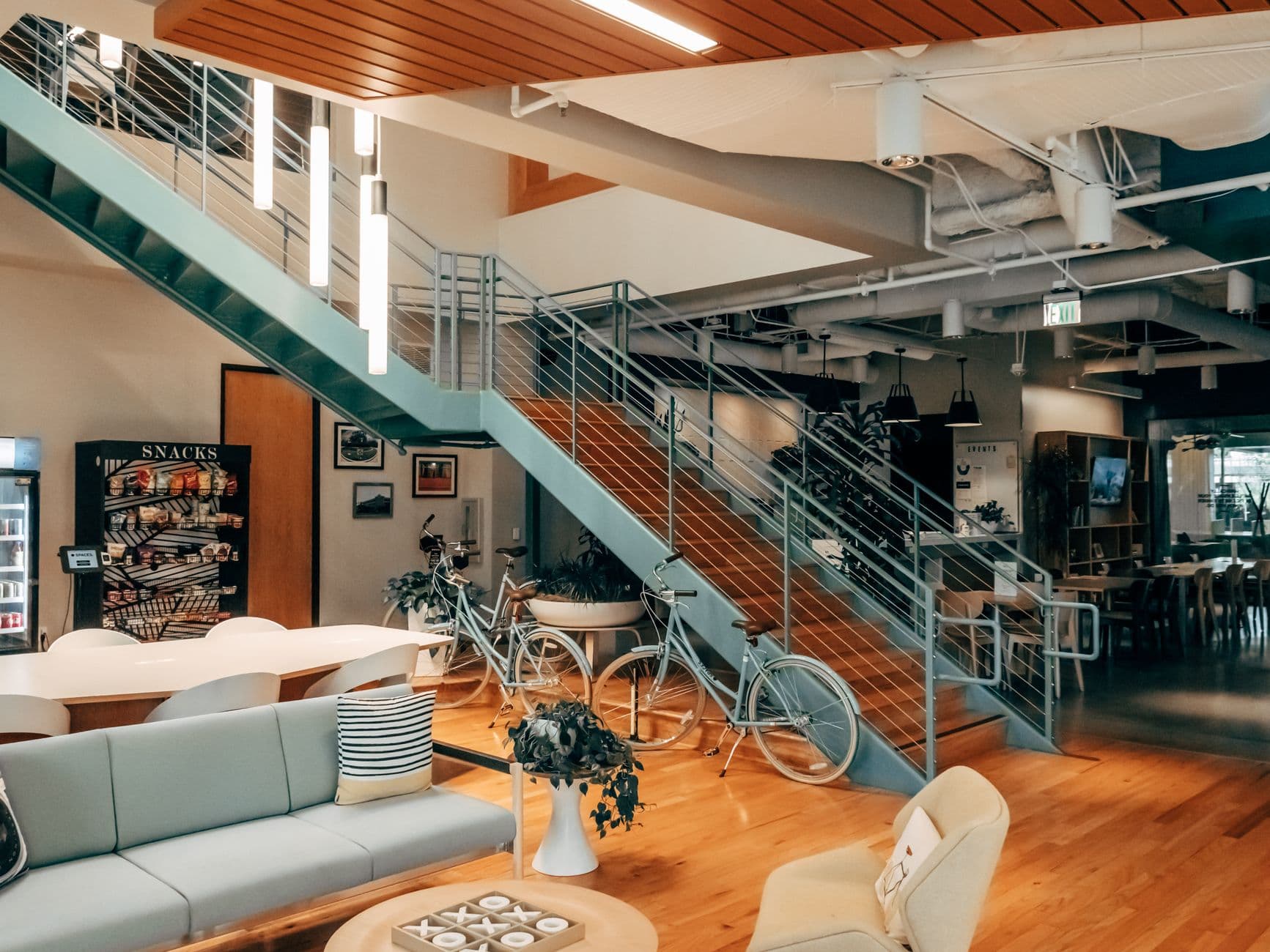 A contemporary open office space with bicycles, sofas, and a snack area, showcasing modern interior design.