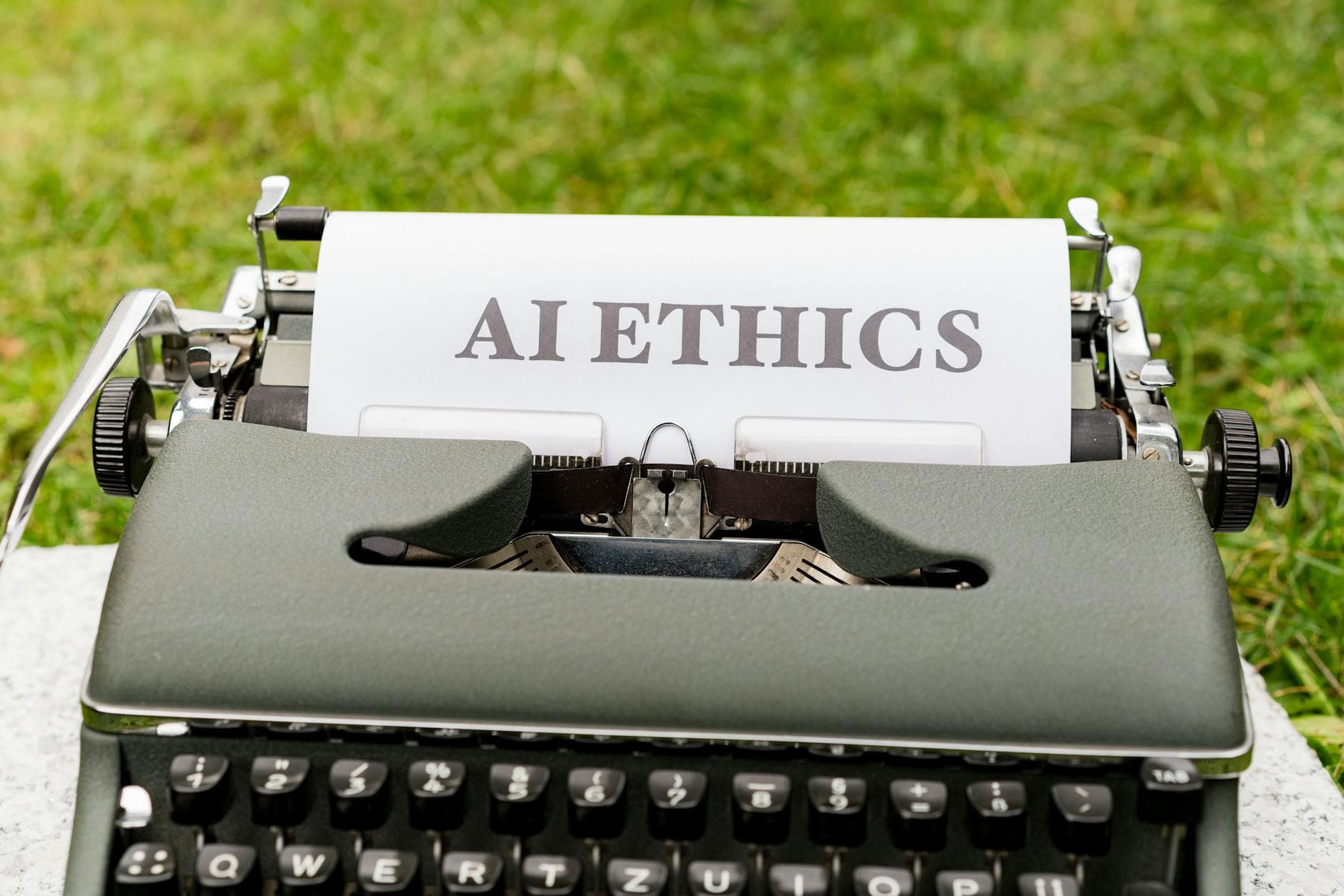 A vintage typewriter outdoors displaying "AI ethics" on paper, symbolizing tradition meets technology.