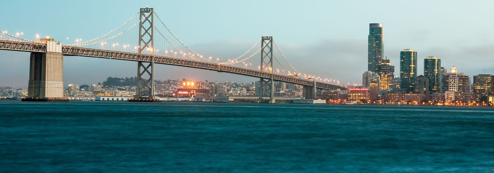 A stunning view of the illuminated Bay Bridge and San Francisco cityscape at twilight.