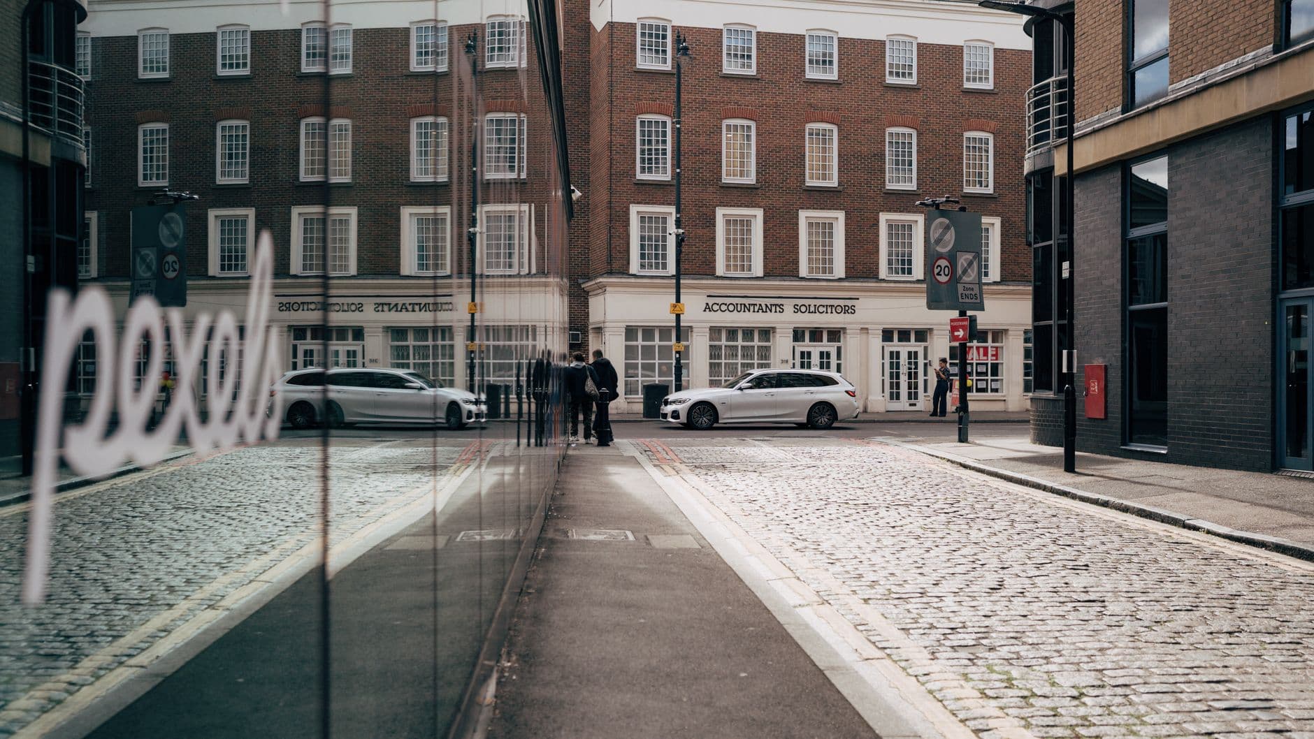 A city street with modern reflections and classic architecture.