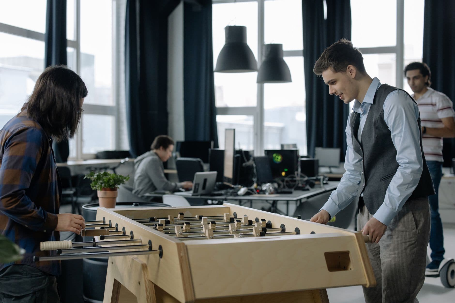 Office workers taking a break to play foosball in a modern startup environment.