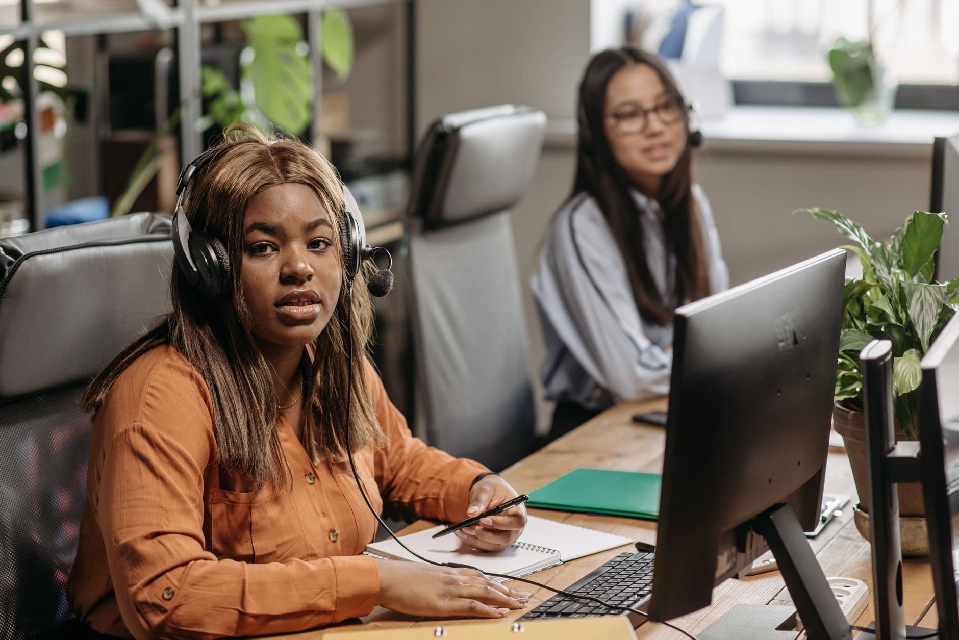 Two diverse women working in a call center, focused and engaged with headsets.
