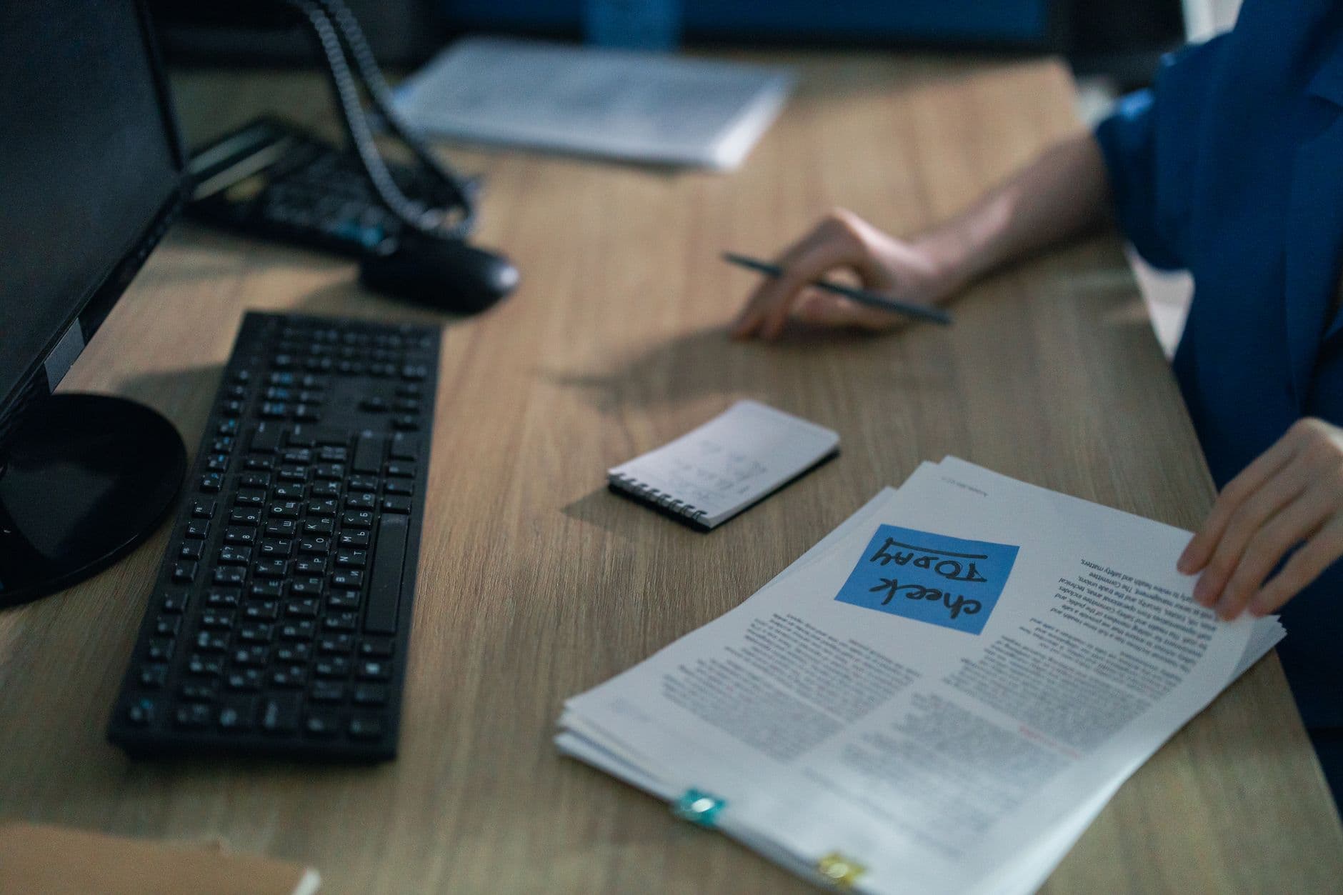A close-up of a computer keyboard and documents on a desk in an office setting, highlighting workplace organization.