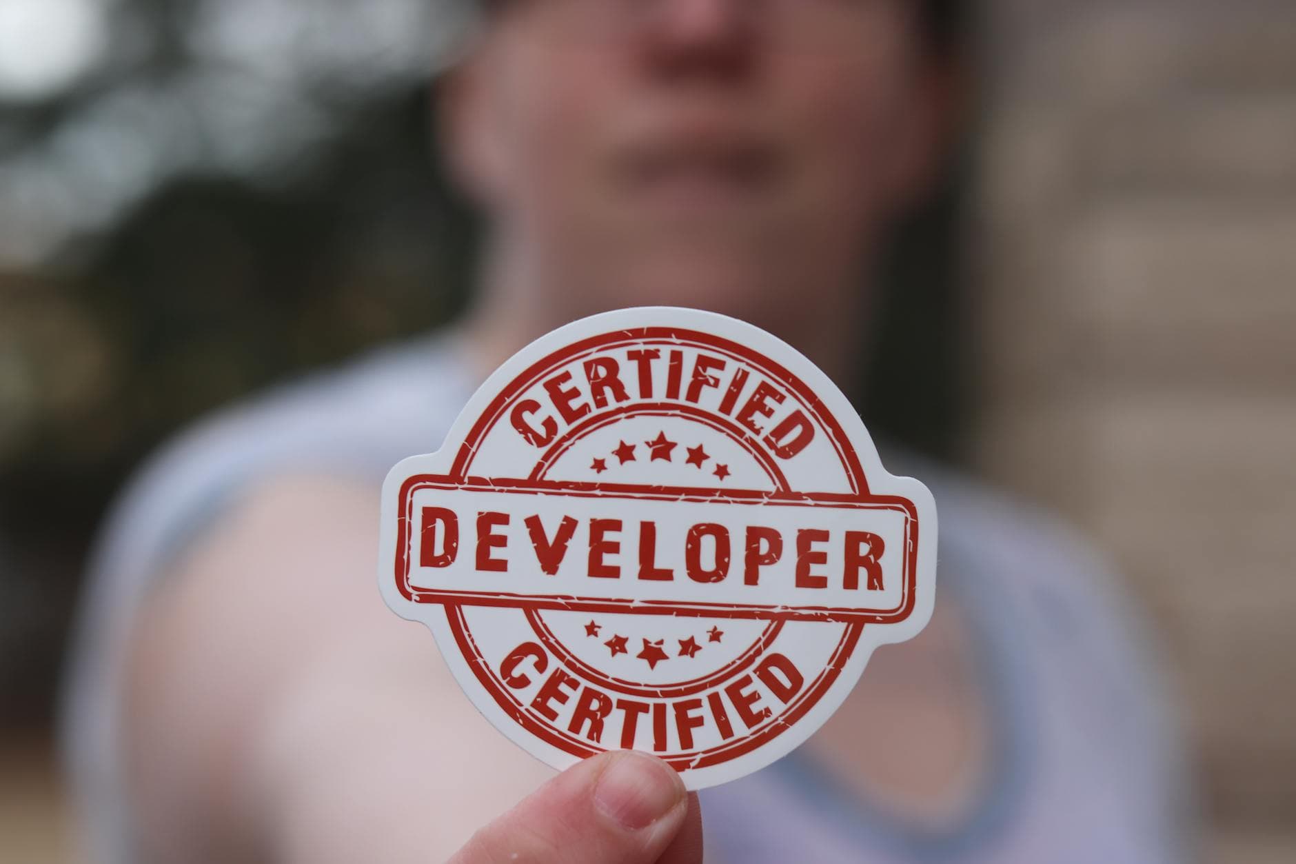 Close-up of a certified developer badge being held outdoors.