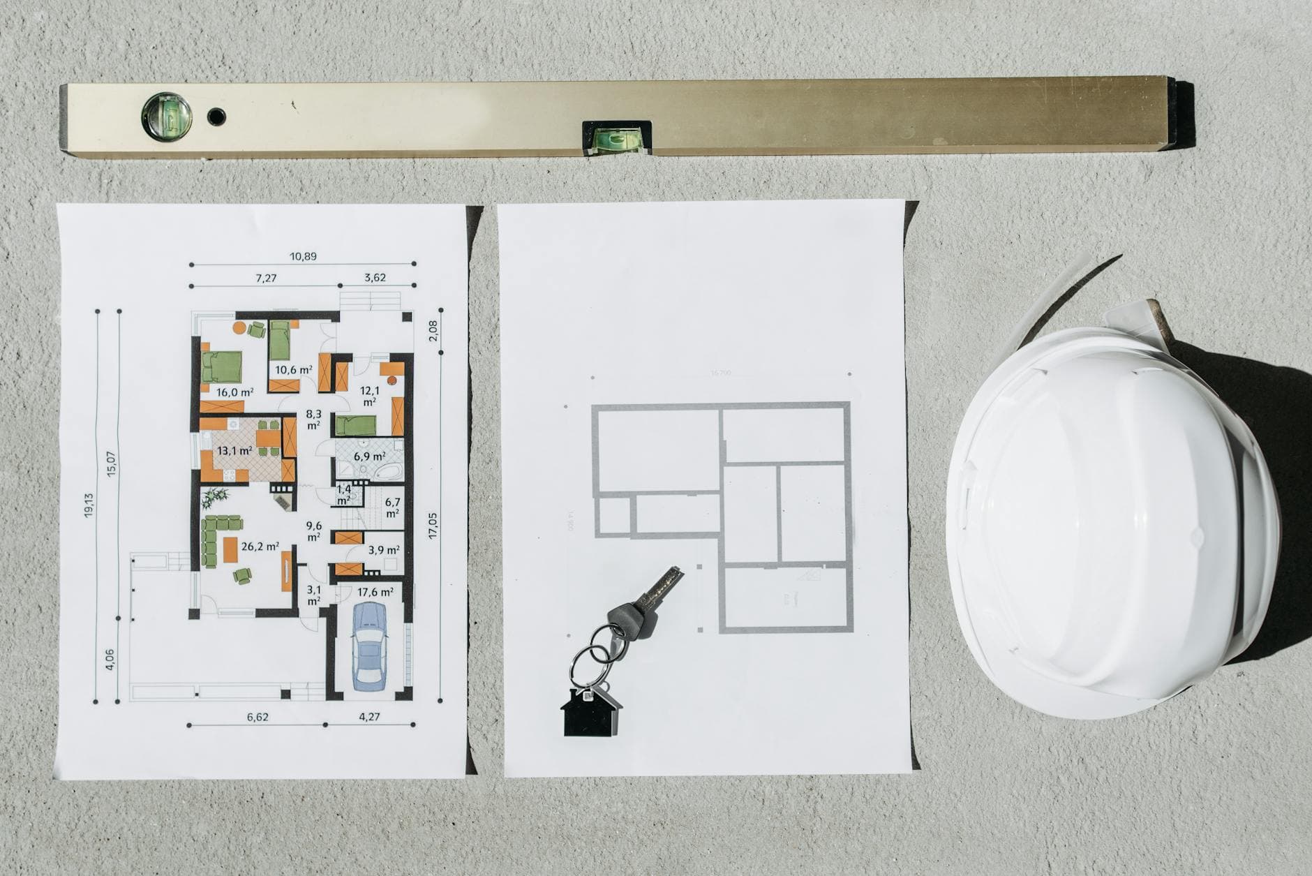 Blueprints, spirit level, and hard hat symbolize house planning.
