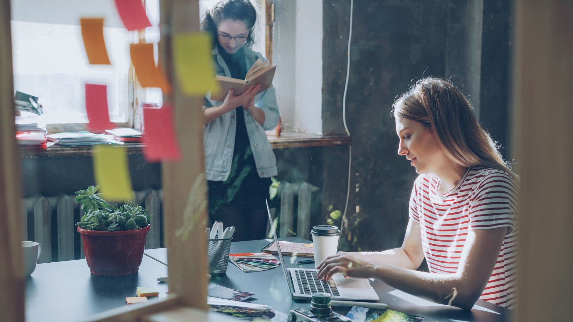 Two women engaged in creative work, collaborating in a stylish office space.
