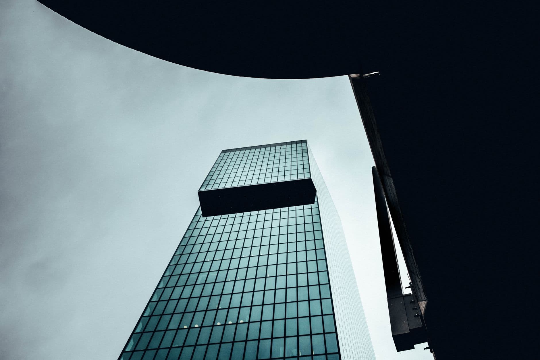 Low angle view of a modern skyscraper in Zurich showcasing sleek architecture against a cloudy sky.