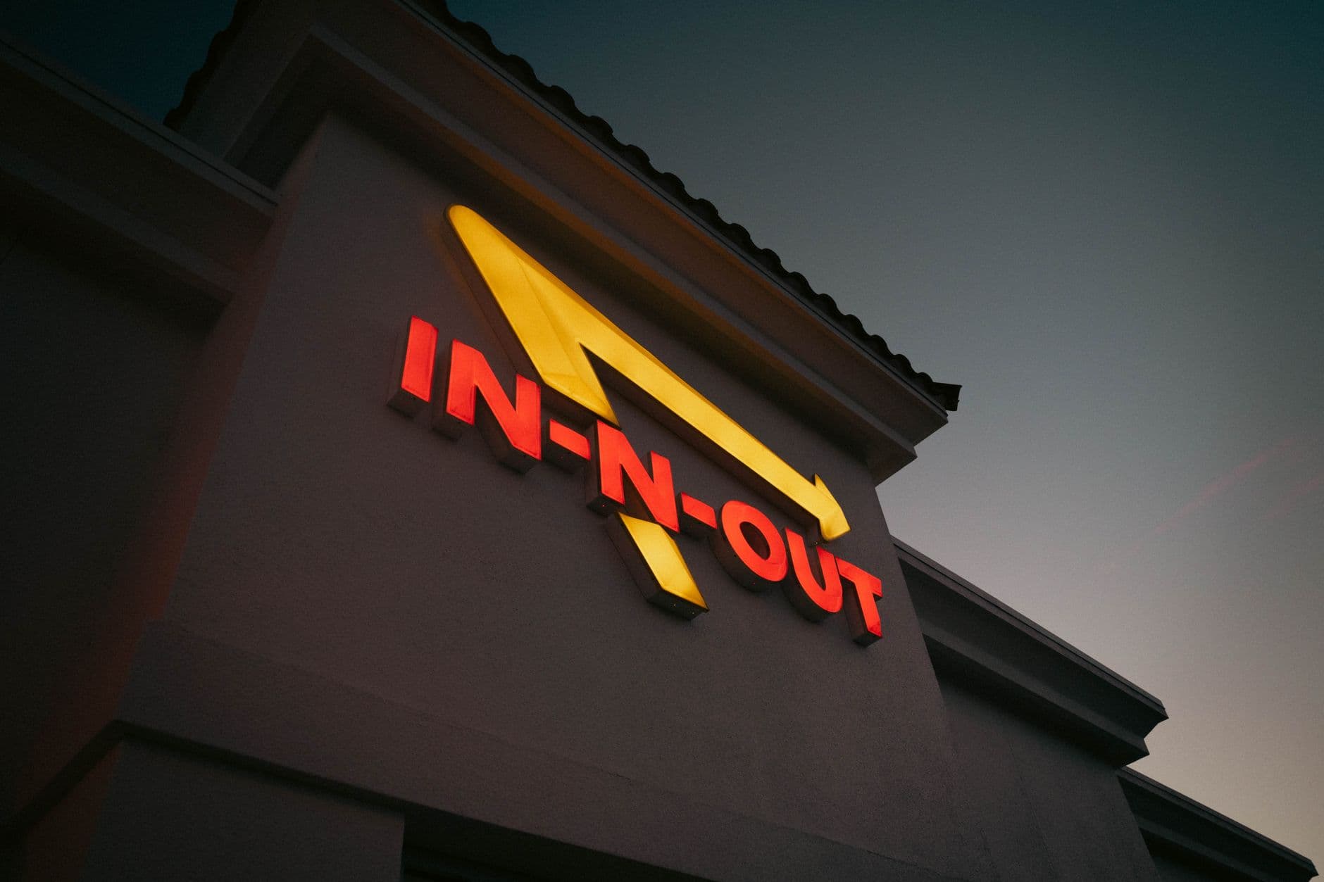 Dramatic shot of In-N-Out Burger sign with vibrant colors at dusk, capturing iconic branding.