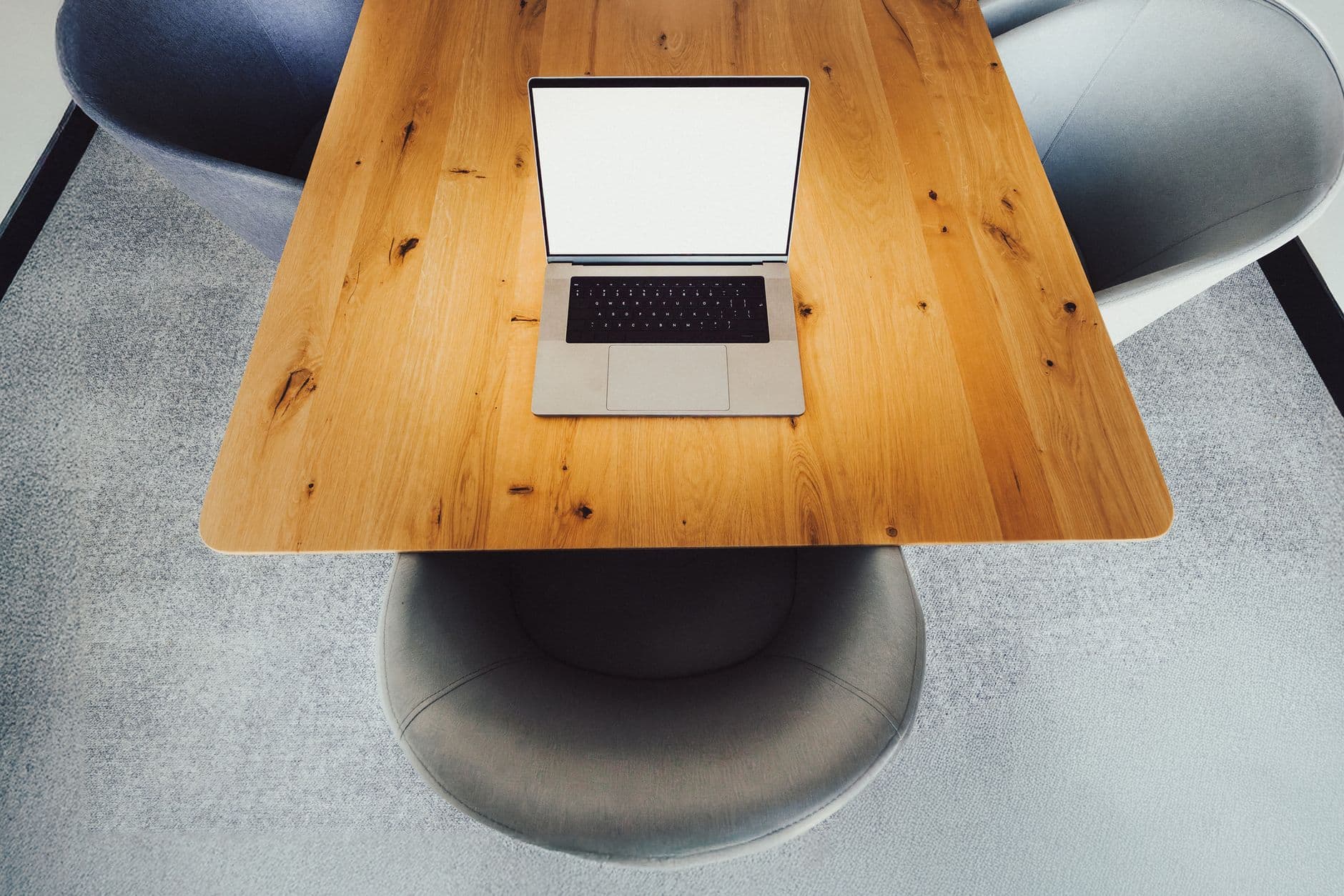 Aerial shot of a modern office desk setup with a laptop and chairs, ideal for corporate presentations.