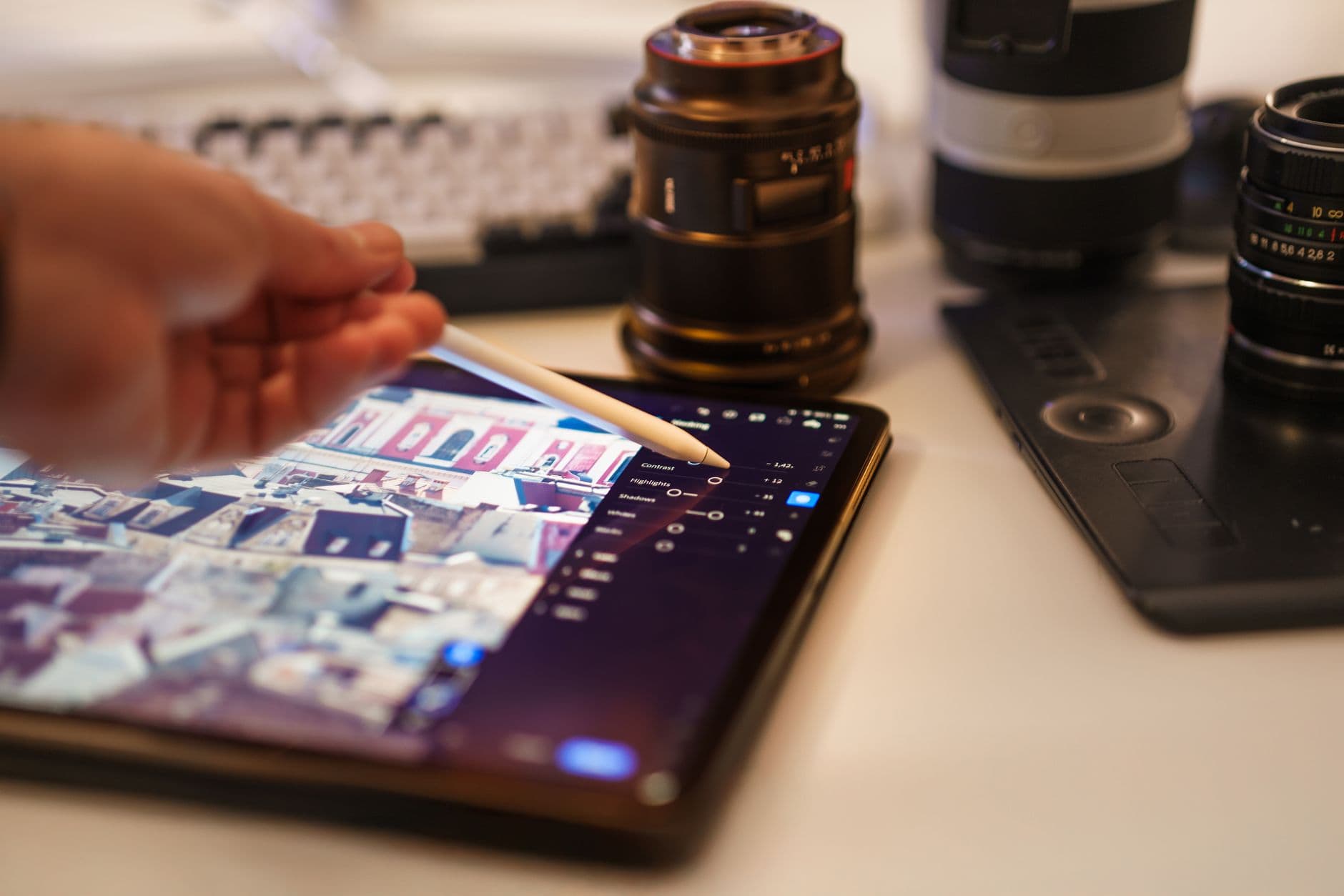 A detailed view of a professional photography editing setup with tablet and lenses.