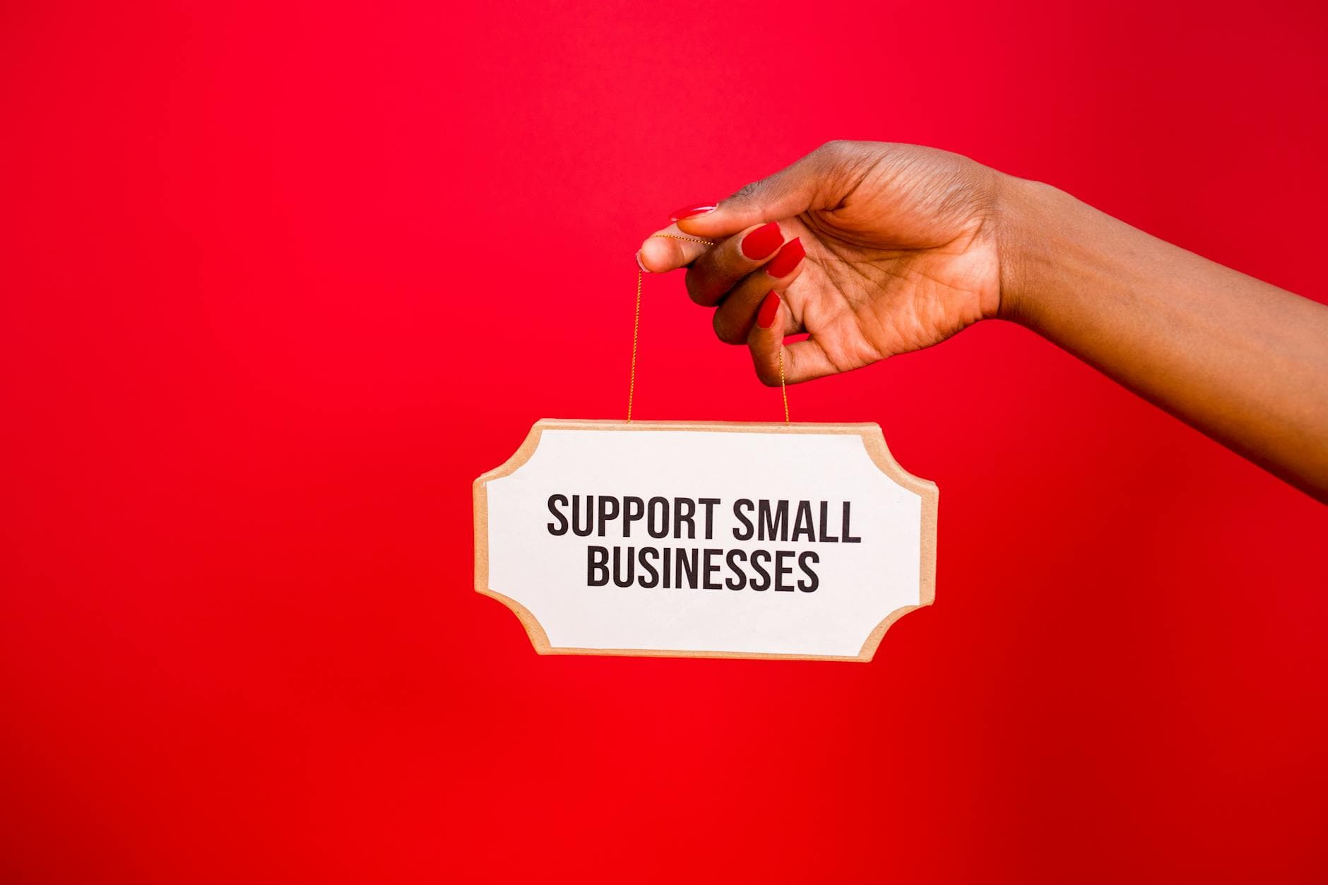 Close-up of a hand holding an inspiring sign encouraging small businesses support.